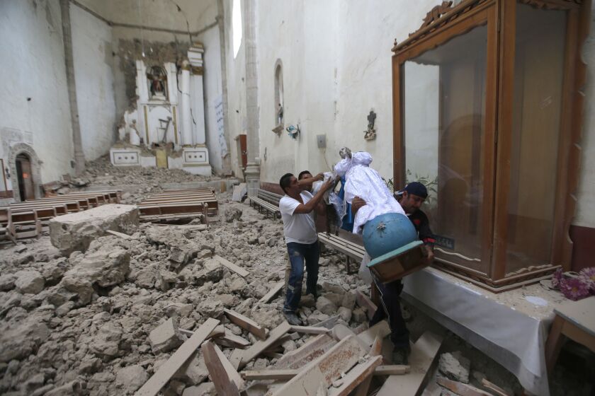 Workers rescue a religious statue from the heavily damaged former convent of San Juan Bautista, in Tlayacapan, Morelos state, Mexico. | Eduardo Verdugo/Associated Press