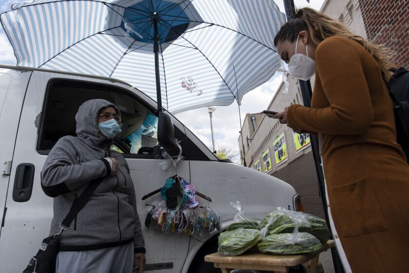 Luz Maria Cortez, right, with Increase the Peace, helps sign up street vendors in Chicago’s Back of the Yards neighborhood for a small grant program to help street vendors during the coronavirus pandemic.
