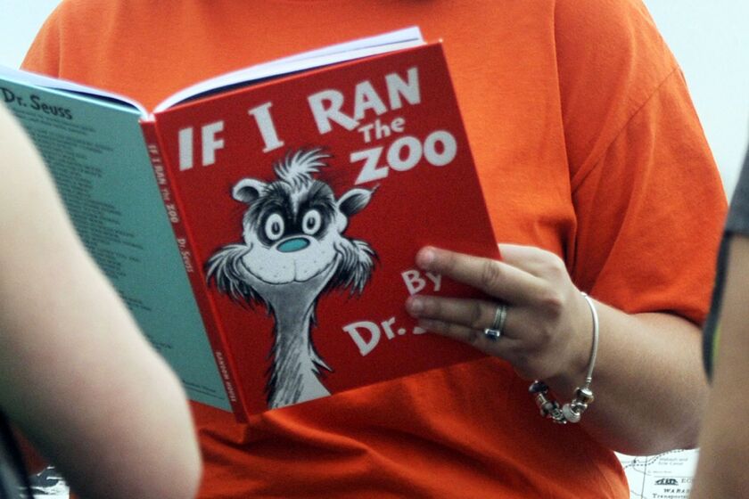 In this 2013, file photo, Courtney Keating, education coordinator of The Literacy Center in Evansville, Ind., reads “If I Ran the Zoo,” By Dr. Seuss, to passersby during an event to promote literacy along the Evansville Riverfront.