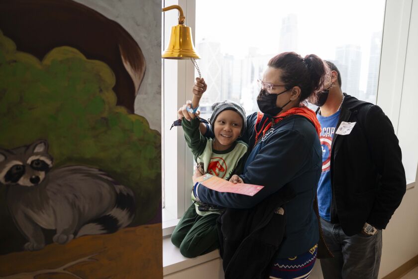 Ethan Lopez, 6, rings a bell to celebrate his last chemotherapy session while his mother Gisela Gama holds him at Ann and Robert H. Lurie Children’s Hospital of Chicago in the Streeterville neighborhood, Friday, Jan. 5, 2024. Kids read a poem and ring a bell whenever they finish their chemotherapy. | Pat Nabong/Sun-Times