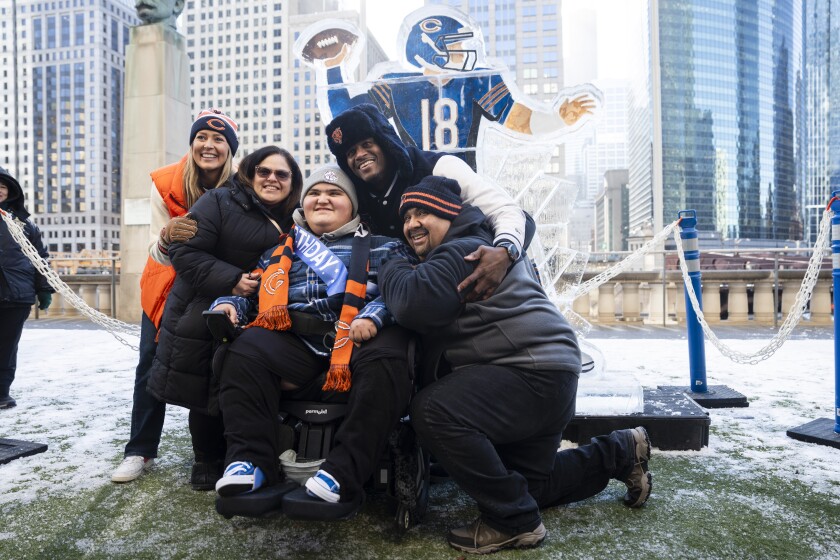 Lily Perez and her husband Kenny Perez take a photo with their son, Noah Perez, and former Chicago Bears player Anthony “Spice” Adams Thursday during an event unveiling an ice sculpture dedicated to quarterback Caleb Williams.| Pat Nabong/Sun-Times