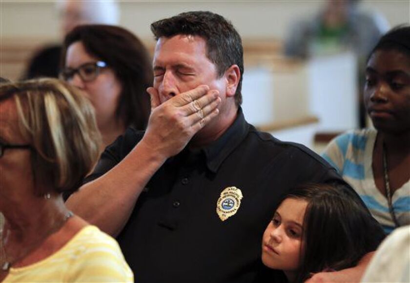 Chuck Hartung holds his daughter Haley, 8, during a prayer service at Wesley Memorial United Methodist Church for the victims of shootings at a recruiting center and another U.S. military site a few miles apart in Chattanooga, Tenn., Thursday, July 16, 20