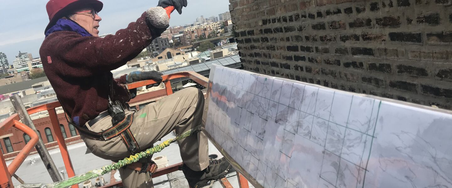 Chicago muralist Thomas Melvin on scaffolding to paint his ivy mural in Fulton Market.