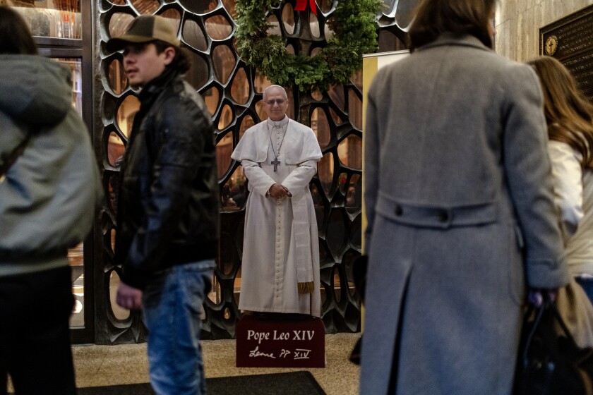 Parishioners stand next to a cardboard cutout of Pope Leo XIV in the main entryway of Holy Name Cathedral on Sunday December 28, 2025.
