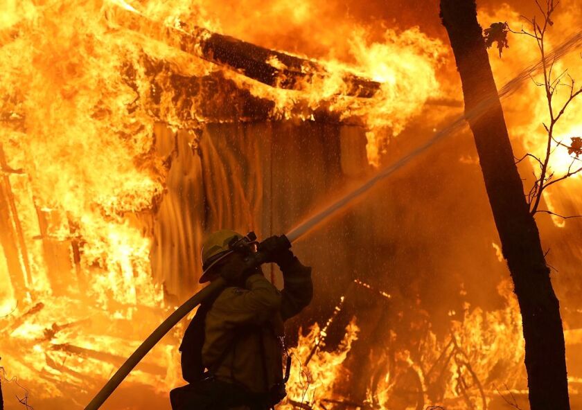 A firefighter monitors a burning home as the Camp Fire moves through the area on November 9, 2018 in Magalia, California. | Getty Images