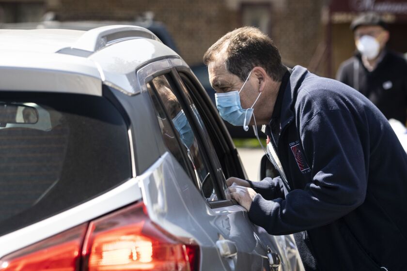 U.S. Rep. Jesus “Chuy” Garcia approaches a vehicle to give out free blue surgical masks and hand sanitizer in Little Village on the Southwest Side, a neighborhood hit hard by the coronavirus pandemic, Wednesday morning, May 13, 2020.