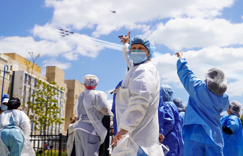 Health care workers at Stroger Hospital watch from the hospital’s main entrance as the U.S. Navy’s Blue Angels fly over Chicago in their honor, Tuesday morning, May 12, 2020.