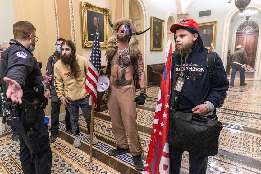 Supporters of President Donald Trump, including Jacob Chansley, center with fur hat, are confronted by Capitol Police officers outside the Senate Chamber inside the Capitol in Washington on Jan. 6, 2021.