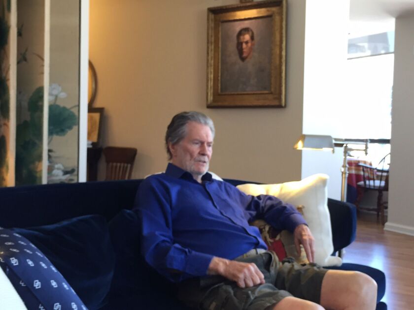 Jay Tunney sits in his Chicago apartment with a portrait of his father, Gene Tunney, in the background. Photo by Neil Steinberg/Sun-Times