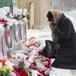 A mourner pays respects at a memorial for the five people killed in a shooting at the Henry Pratt Company in Aurora in February.