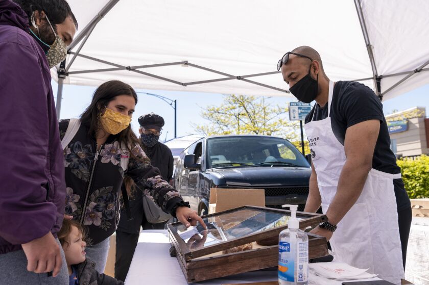 A family chooses which doughnuts to buy from Virgil Roundtree and his stall Downstate Doughnuts at the Andersonville Farmers Market, Wednesday, May 12, 2021.