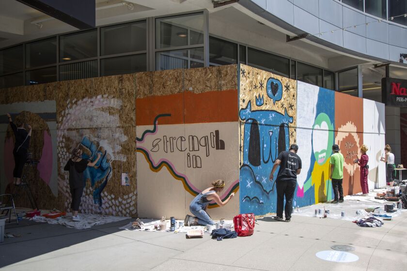Artists work on their murals at the Roosevelt Collection Shops on 150 W Roosevelt Rd, in South Loop, Chicago, Monday June 15, 2020. More than twenty artists from Chicago were invited to create works of art on plywood at the Chicago Showplace Icon in an effort to promote peace and equality for all. | Anthony Vazquez/Sun-Times