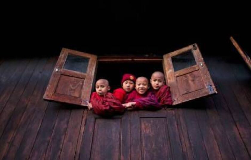 Novice Buddhist monks peep out of a monastery window to watch Taíang National Liberation army (TNLA) leaders who gathered in Mar Wong, a village in northern Shan state, Myanmar to celebrate the 52nd anniversary of their insurrection. (AP Photo/Gemunu Ama