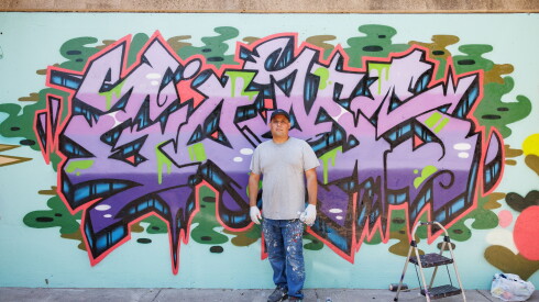 Alex Mendoza stands in front of his mural.