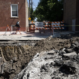 A resident walks to the trash bin near a construction site for flood mitigation infrastructure in the 5500 block of W. LeMoyne Street in Austin.