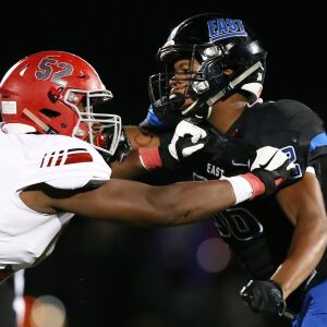 Lincoln-Way East’s Adrian Wilson, right, locks up with an offensive lineman. Allen Cunningham/For the Sun-Times.