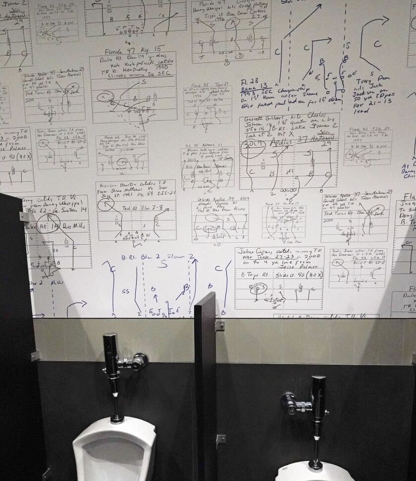 Football plays designed by Steve Spurrier from years past are displayed on wallpaper in a restroom at his new restaurant, the Gridiron Grill, in Gainesville, Florida.