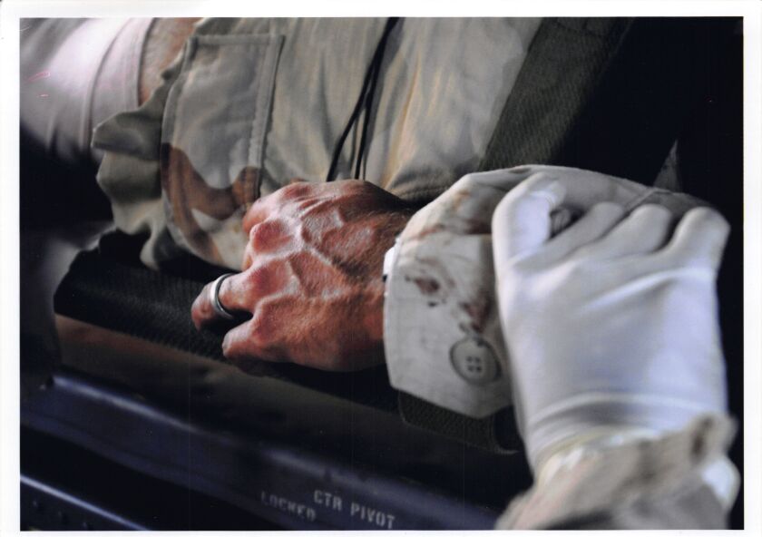 A closeup of then-Sgt. Jim Rudisill’s hand, with another person’s gloved hand holding his wrist, as he was medically evacuated from Diyala Province, Iraq, in 2005. He sustained multiple injuries and says he also saw the toll war took on his comrades.