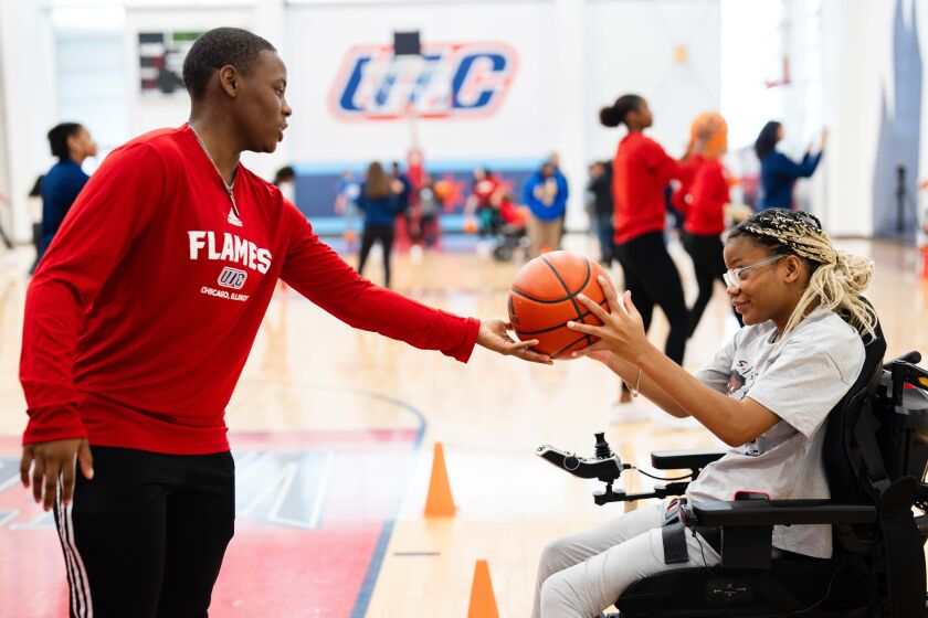 Erin Henry, of the UIC Flames women’s basketball team, gives a ball to Raven Harvey, a Beautiful Lives Project participant, during the Court of Dreams event at the University of Illinois Chicago’s Flames Athletic Center in the Little Italy neighborhood, Thursday, Oct. 19. Members of the UIC Flames women’s basketball team taught basketball skills to participants of the Beautiful Lives Project, which organizes events for people with disabilities.