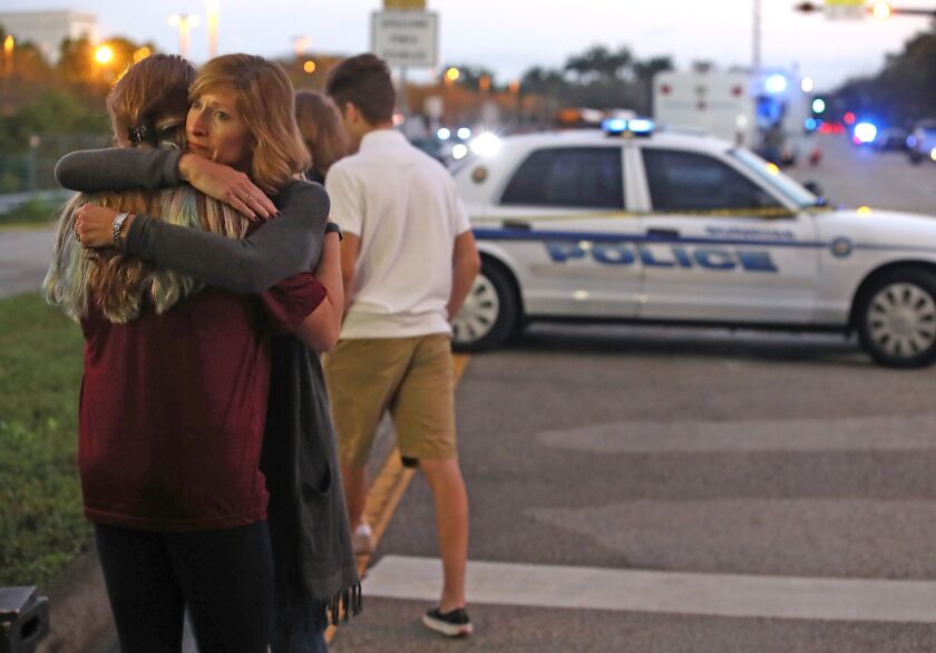 Kristi Gilroy hugs a young woman at a police checkpoint near Marjory Stoneman Douglas High School in Parkland, Fla., where 17 people were killed by a gunman Wednesday. Police arrested the suspect after a short manhunt, and have identified him as 19-year-o