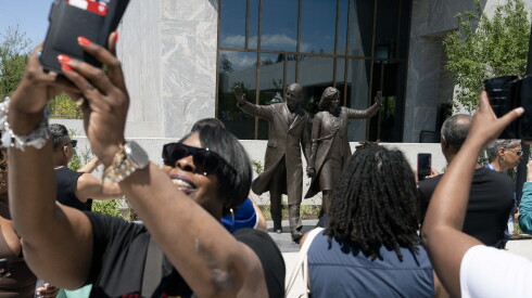 People take pictures, including selfies, of the statue of former President Barack Obama and first lady Michelle Obama on the John Lewis Plaza at the Obama Presidential Center, during opening day Friday, June 19, 2026.