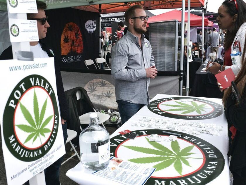 A worker stands at a booth advertising Pot Valet, a Los Angeles-based delivery service for cannabis. | AP file photo