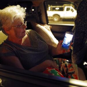 Volcano evacuee Stella Calio watches social media videos of the volcanic eruption. | AP Photo