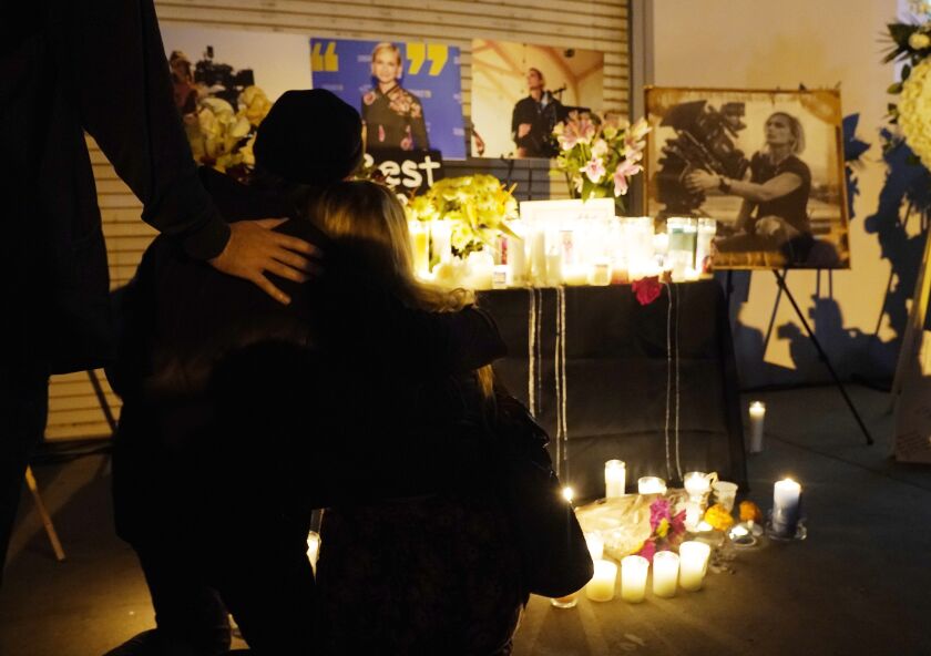 Attendees embrace at a candlelight vigil for the late cinematographer Halyna Hutchins, pictured in photographs in the background, on Sunday, Oct. 24, 2021, in Burbank, California.