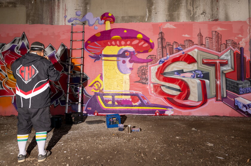 Street artist Joey D. works on his section of the collaborative mural.
