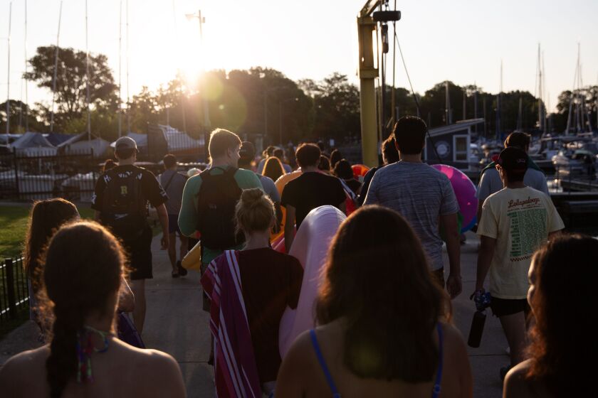 People walk toward Montrose Harbor for Friday Morning Swim Club on Friday, Aug. 4, 2023.