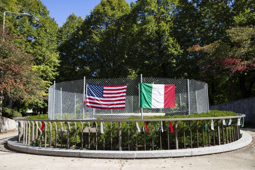 A fence with the U.S. and Italian flags cover the area where a Christopher Columbus statue once stood at Arrigo Park in University Village / Little Italy, Thursday, Oct. 8, 2020.