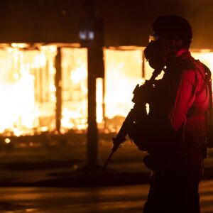 A member of the Wisconsin National Guard stands watch outside B&L Office Furniture Inc. at 1101 60th St. in Kenosha, one of several businesses to burn during the second night of unrest after police shot Jacob Blake, Monday night, Aug. 24, 2020.