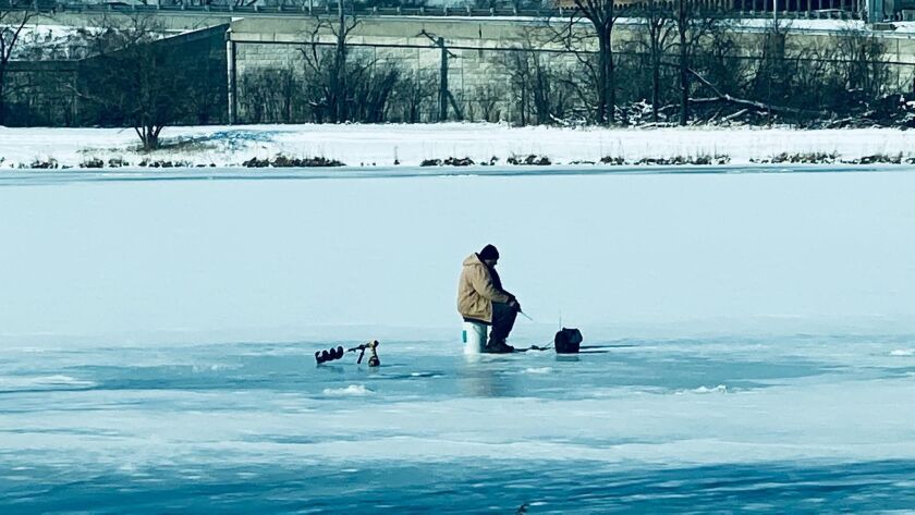 An ice angler sits on a partially snow-covered Axehead Lake on Friday before the storm. Reader provided