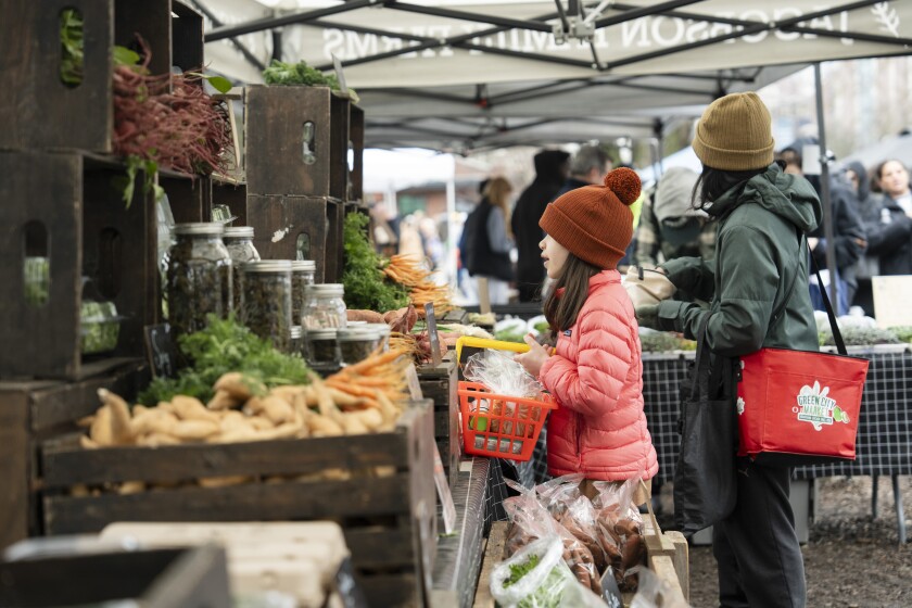 Customers visit Jacobson Family Farms' stand in Lincoln Park on the first day of Green City Market in April 2025.