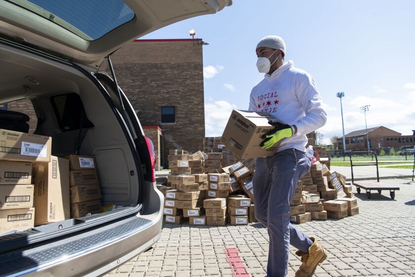 Todd Belcore, executive director of the nonprofit Social Change, loads boxes of food into a waiting minivan outside Bronzeville Academy Charter School on the South Side, Friday afternoon, May 8, 2020.