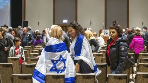 Two women wrapped in Israeli flags are among the attendees of a vigil in support of Israel on Monday evening at the Westin Chicago North Shore in Wheeling.
