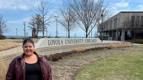 Student Sheridan Gorman stands next to a sign that reads Loyola University Chicago.