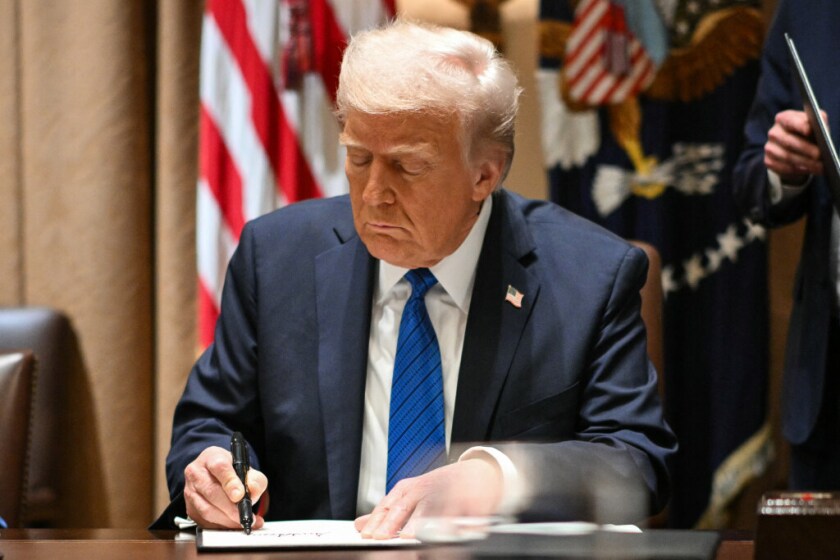 President Donald Trump signs executive orders during a meeting with U.S. ambassadors in the Cabinet Room of the White House Tuesday.