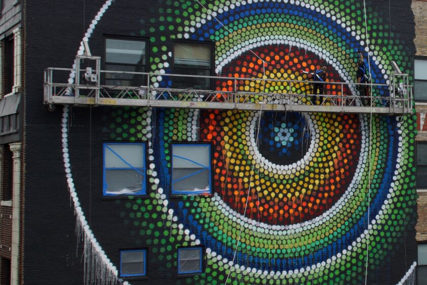 Joe Miller and Sunni DiLuzio working from a swing stage on the mural “Uptown Dot King.”