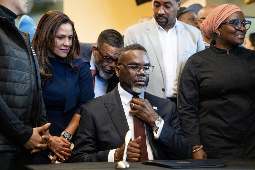 Ald. Chris Taliaferro speaks to Chicago Mayor Brandon Johnson before he signs a document to veto the plan to freeze the subminimum wage for tipped workers.