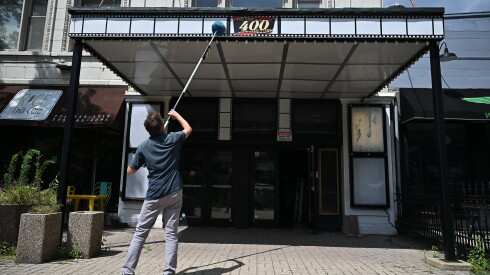 William Chipps uses an extension pole duster to clean the marquee above the entrance at The 400 Theater on Friday, July 24, 2026