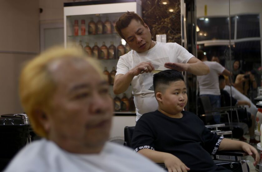 Le Phuc Hai, 66, left, and To Gia Huy, 9, have Trump and Kim haircuts in Hanoi, Vietnam, on Tuesday, Feb. 19, 2019. U.S. President Donald Trump and North Korean leader Kim Jong Un have become the latest style icons in Hanoi, a week before their second sum