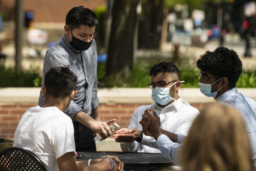 General manager Juan Becerril, 35, of Chicago, dispenses hand sanitizer to customers preparing to eat lunch on the patio at Flat Top Grill in Evanston in May.