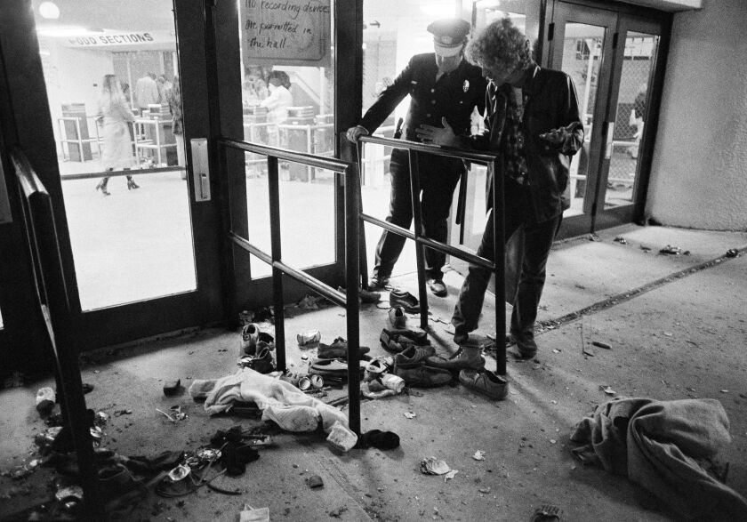 A security guard and an unidentified man look at an area with shows and clothes strewn around where several people were killed and others injured as they were caught in a surging crowd entering Cincinnati’s Riverfront Coliseum for a Who concert on Dec. 3, 1979.