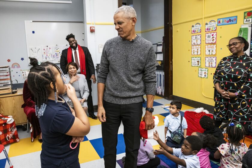 Former President Barack Obama chats with fourth-grade student Kaliyah Montgomery, 9, during a surprise visit to a pre-kindergarten class at Parkside Community Academy in South Shore, Tuesday, Dec. 12.