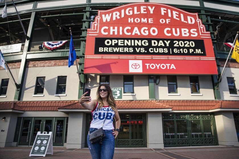 Fans take selfies outside Wrigley Field shortly before the start of the opening day game between the Chicago Cubs and the Milwaukee Brewers, Friday evening, July 24, 2020.