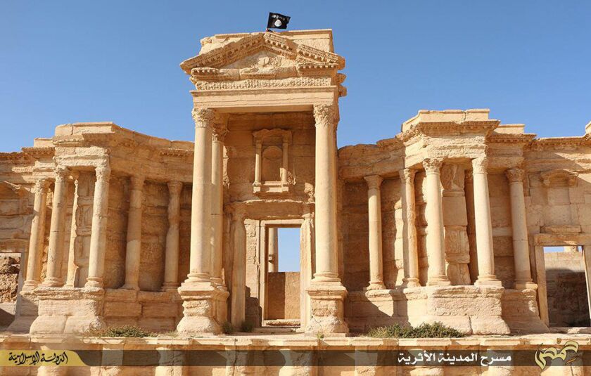 A flag of the Islamic State group fluttering atop the circular wall bounding the orchestra at the Roman theatre of the ancient city of Palmyra, a 2,000-year-old metropolis and an Unesco world heritage site located 215 kilometres northeast of Damascus. | A
