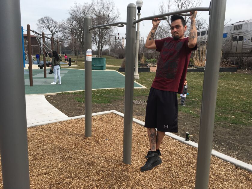 Giovanny Ortiz, 23, uses the new adult fitness equipment at Rutherford Sayre Park while his wife, Rina, 23, and their kids, ages 2 and 3, play on the swings. Photo by Dan Mihalopoulos.
