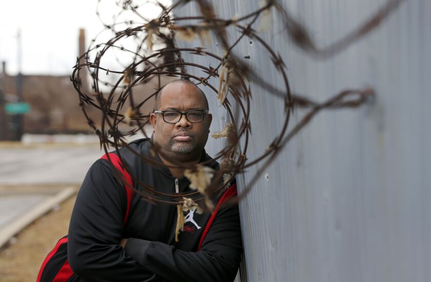 Pastor Corey Brooks of the New Beginnings Church stands near an under-maintained security wall that hugs the sprawling Norfolk Southern train yard and his church on Chicago’s South Side. | AP