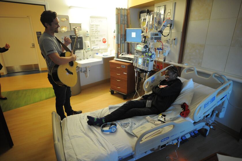 At his bedside, Darius Robey, 18, enjoys a performance by Musicians on Call volunteer Phil Fensel at Ann & Robert H. Lurie Children’s Hospital in Chicago.